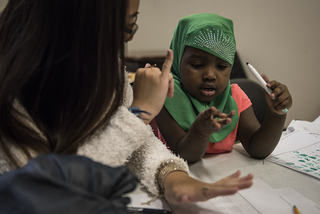 A volunteer helps a young girl with a math problem during RISE's after-school program, which takes place Monday to Thursday.